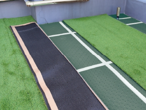 仮敷きしたリアリーターフ®の片側を裏返し、裏側のバッキング面の外周に両面テープを貼ります。